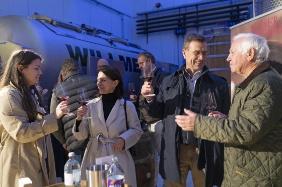 Gäste bei der Weintaufe stoßen mit Wein an