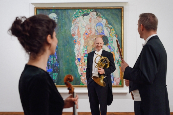 Drei Musiker vor einem Klimt-Gemälde
