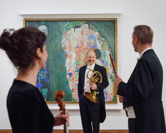 Drei Musiker vor einem Klimt-Gemälde