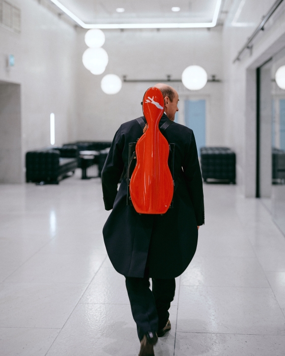 Musiker mit roten Geigenkoffer am Rücken