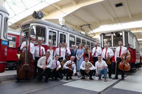 Musiker:innen vor zwei alten Wiener Straßenbahnen