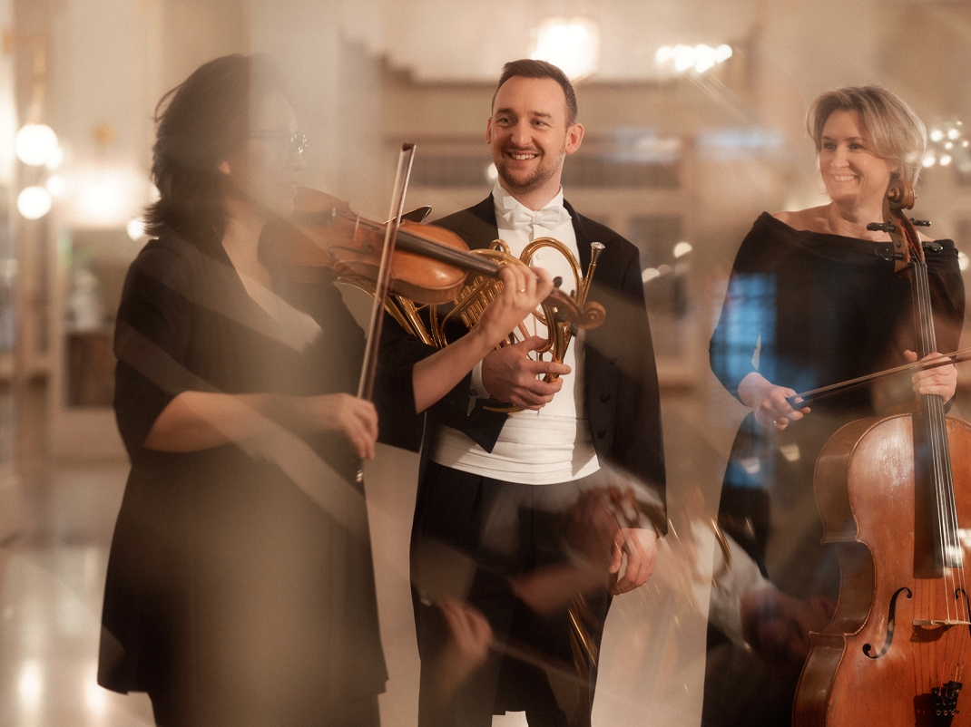 Drei Musiker:innen mit Instrumenten im Konzerthausfoyer