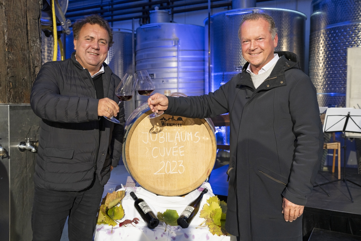 Jan Nast und Fritz Wieninger stoßen vor einem Weinfass an