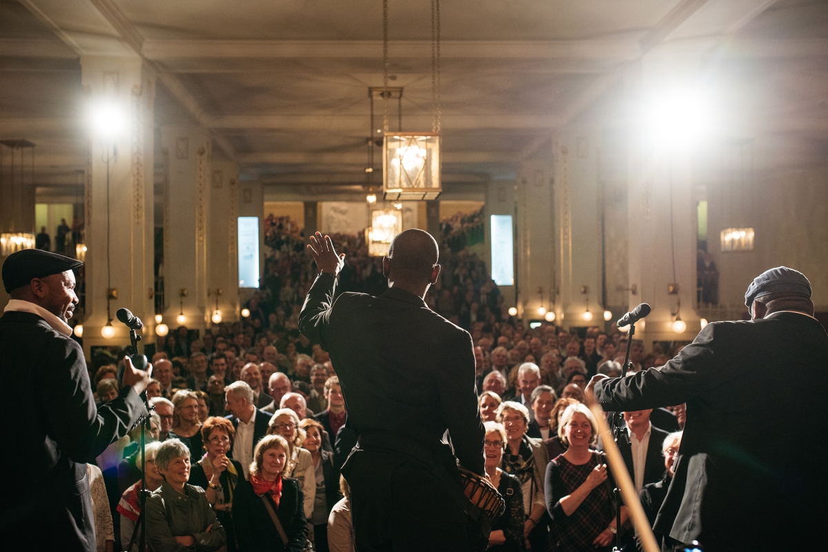 Drei Musiker auf der Bühne im Konzerthausfoyer vor Publikum 