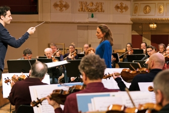 Foto eines dirigierenden Mannes und einem musizierenden Orchester