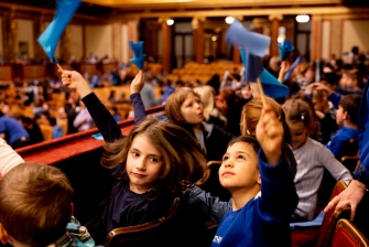 Kinder schwenken blaue Flaggen im Musikverein