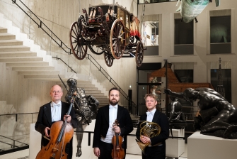 Drei Musiker im Wien Museum unter einer Kutsche
