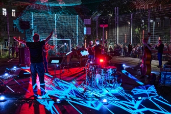 Musiker in einem Spielkäfig im bunten Scheinwerferlicht