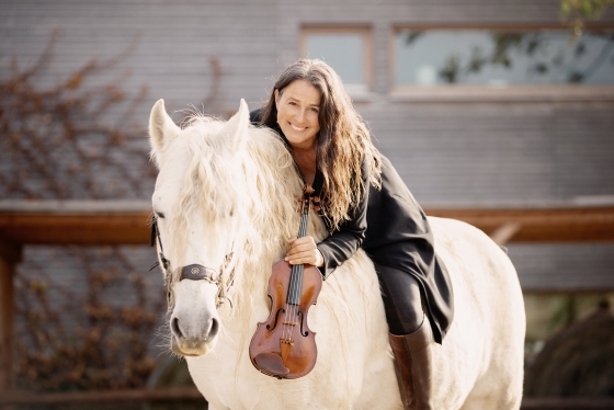 Foto von Birgit Zalodek auf einem Pferd mit einer Violine in der Hand