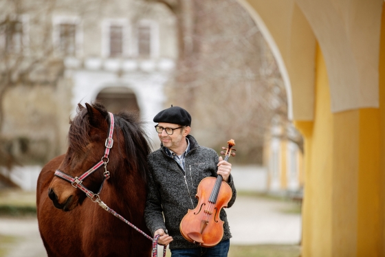 Foto von Ulrich Schönauer, neben einem Pferd, mit einer Bratsche in der Hand